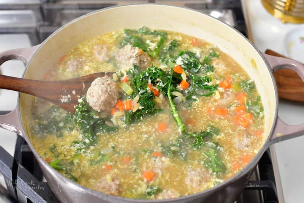 Italian wedding soup in a pot on the stove with a ladle