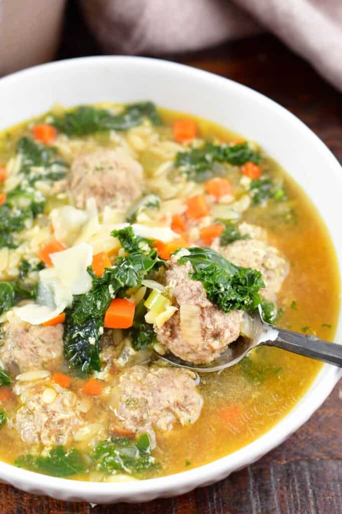 spooning out some meatballs out of the bowl with soup