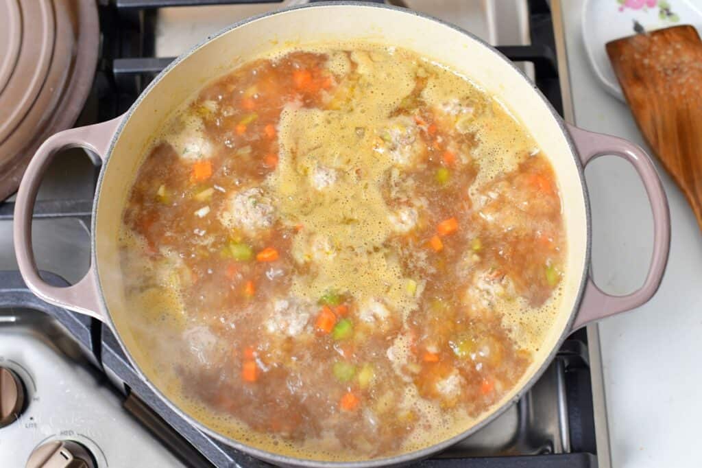 clear soup with meatballs simmering in a pot