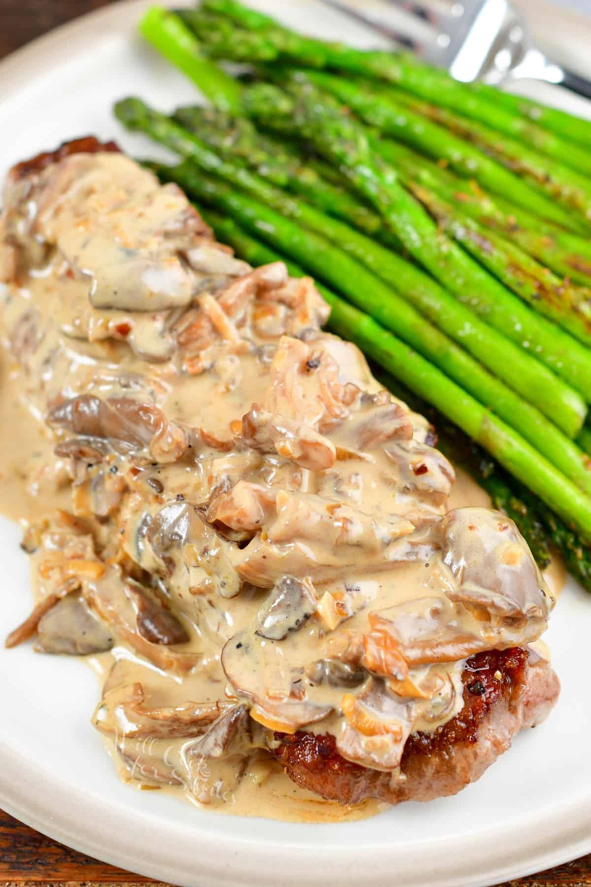 steak topped with creamy mushroom sauce and asparagus