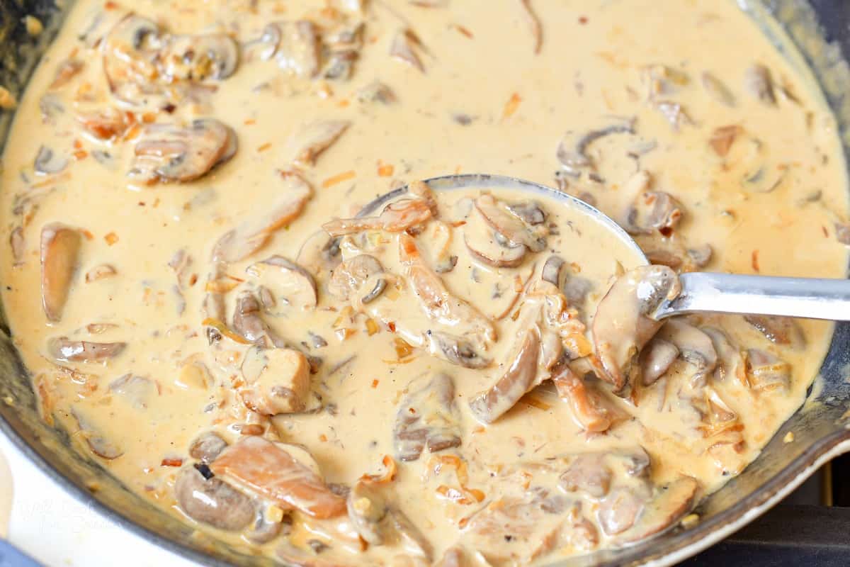 spooning some creamy mushroom sauce from the pan