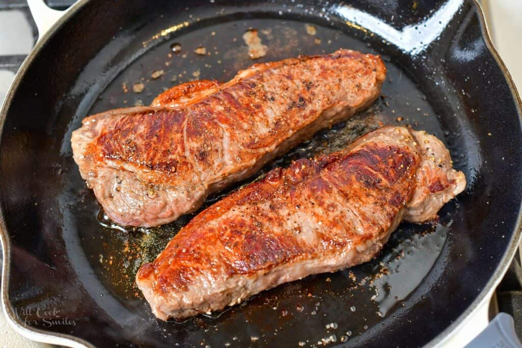 two steaks cooking in the pan