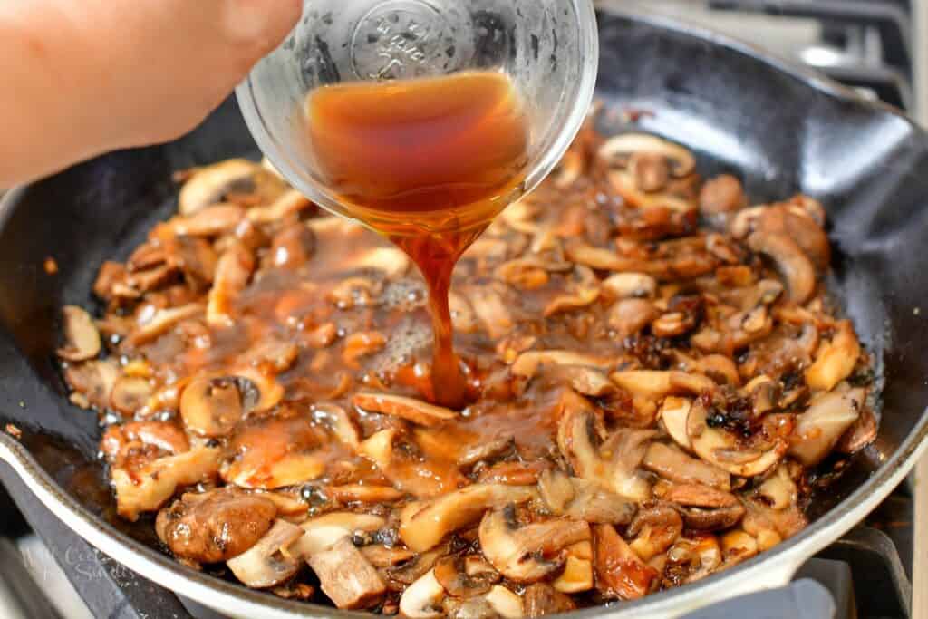 adding beef stock to the pan with mushrooms