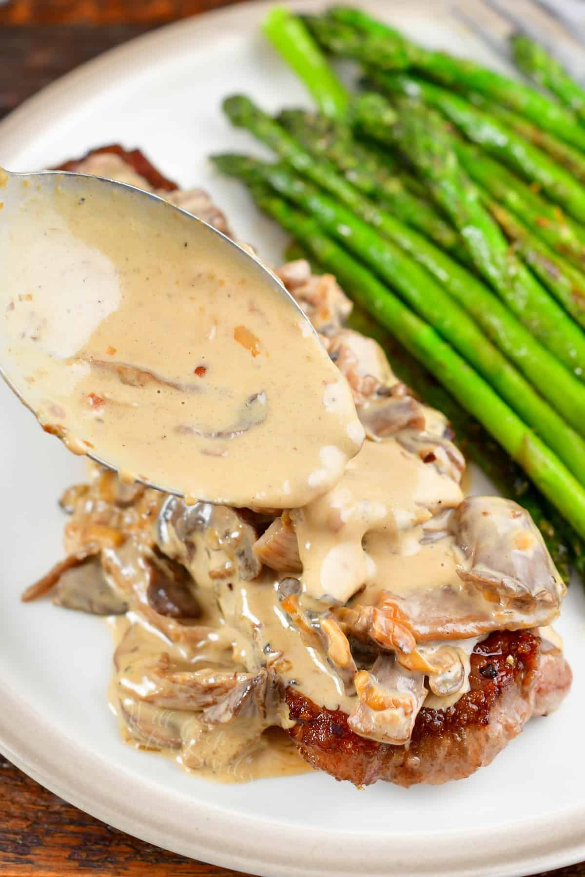 spreading sauce over mushroom sauce topped steak