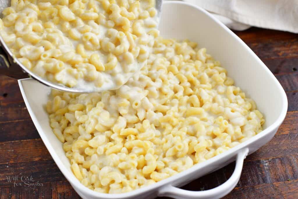 adding mac and cheese to the baking dish