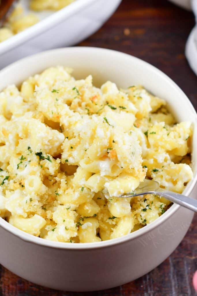 spooning mac and cheese out of a bowl with a fork