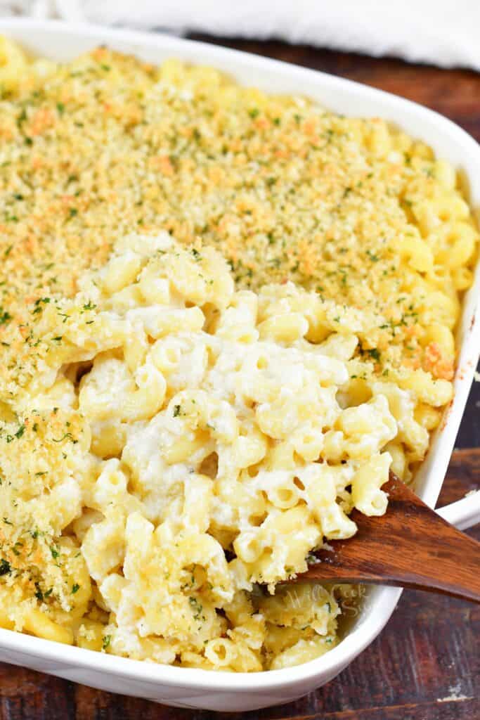 scooping mac and cheese out of the baking dish with a spoon