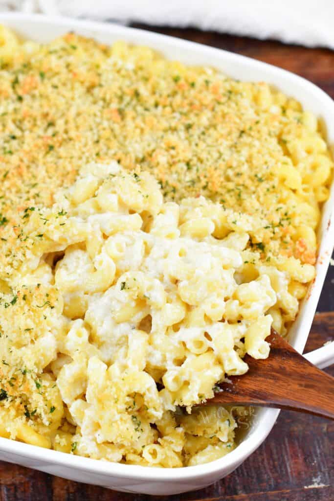 scooping mac and cheese out of the baking dish with a spoon