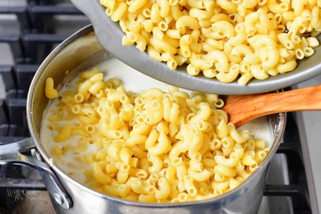 adding macaroni to the pot with cheese sauce