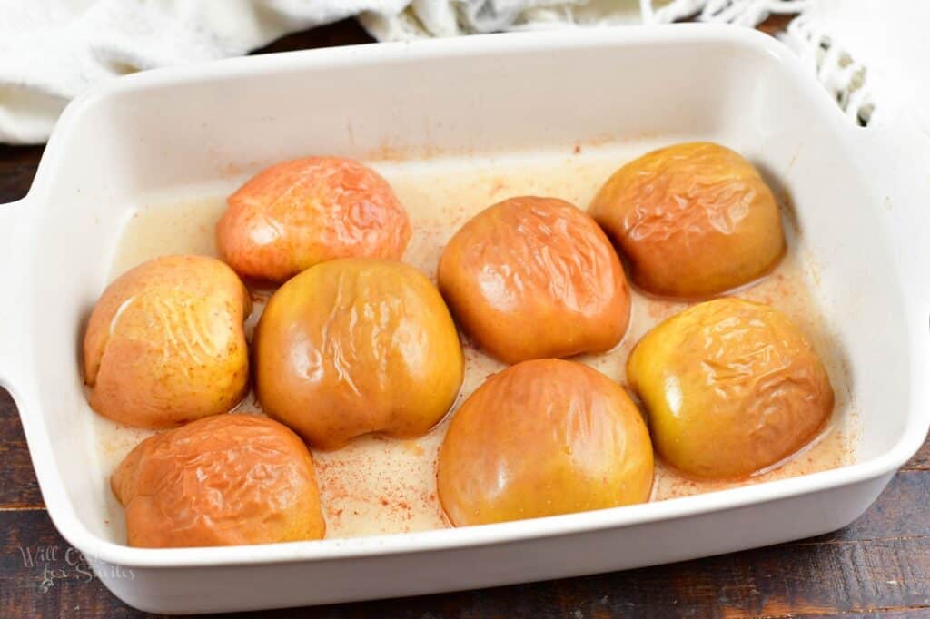 baked apple halves in a white baking dish