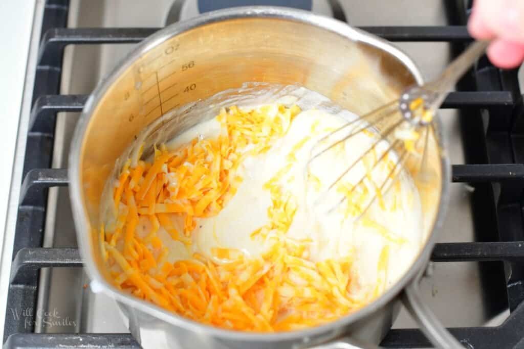 whisking shredded cheese with milk in a pot