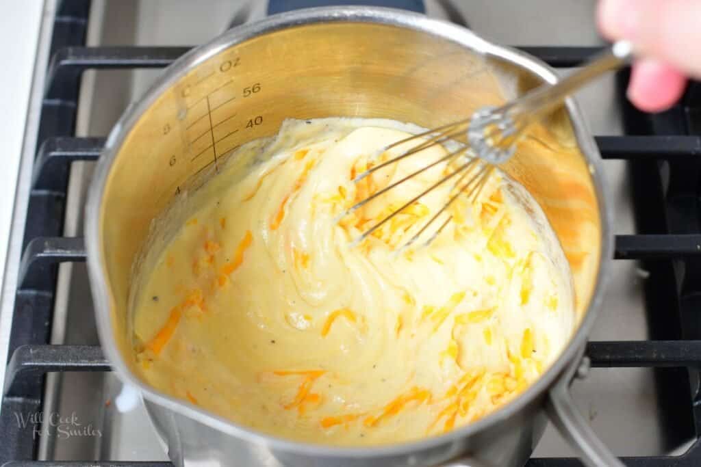 whisking in shredded cheese into the milk mixture