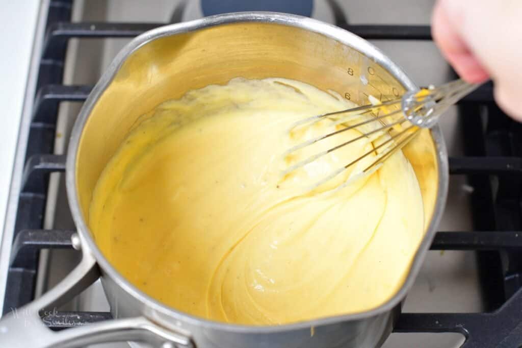 whisking cheese sauce slowly in the sauce pot