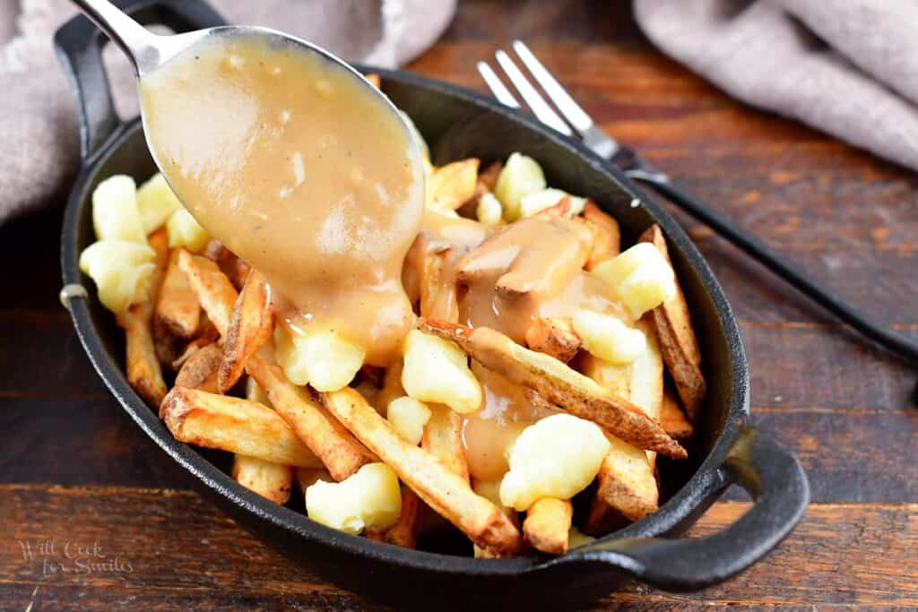 adding gravy on top of fries and cheese