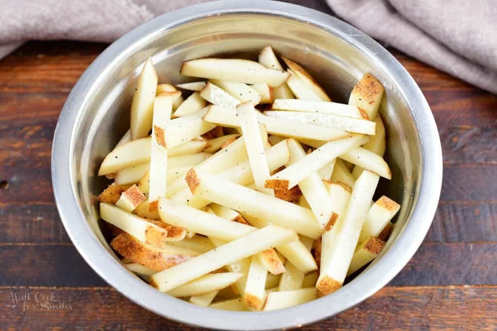 cut and seasoned fries in a mixing bowl
