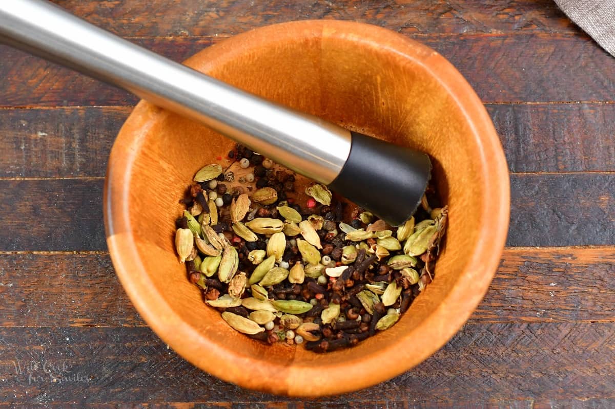 crushing some whole spices with a muddler.