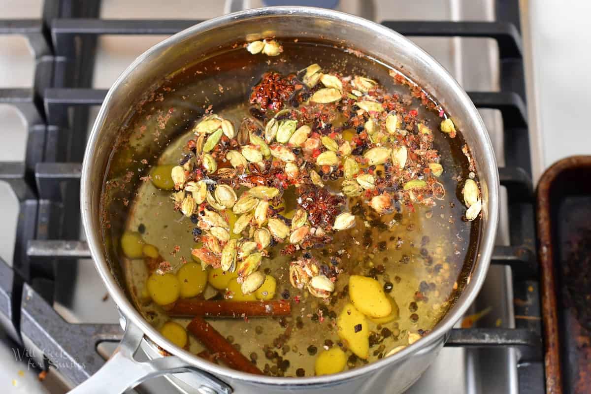 water in a pot with spices added for chai.