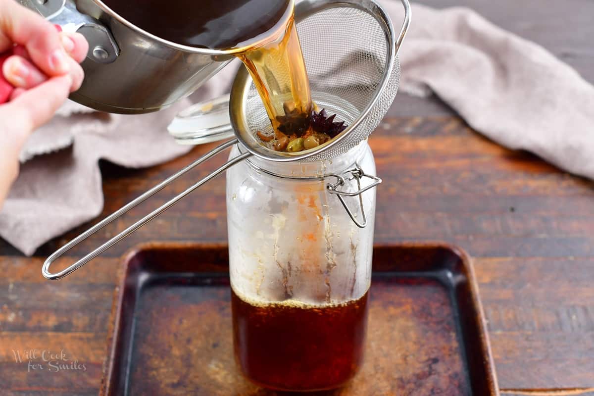 pouring tea through the strainer into the glass jar.