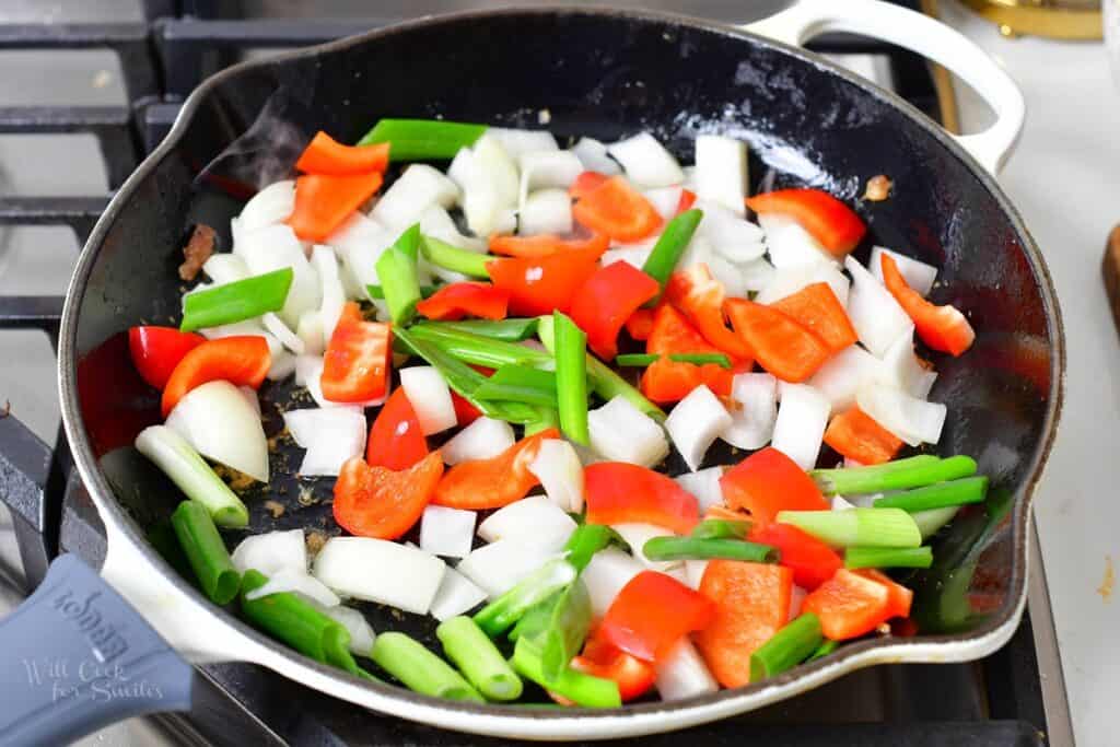 onions and peppers cooking in a pan