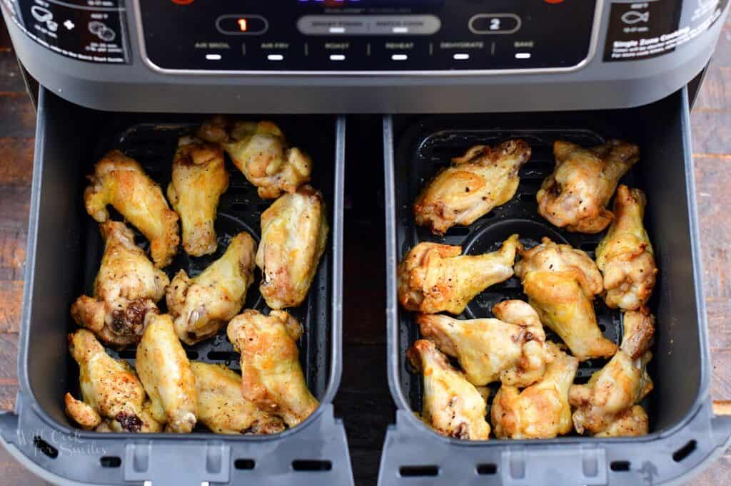 partially cooked chicken wings in the air-fryer baskets