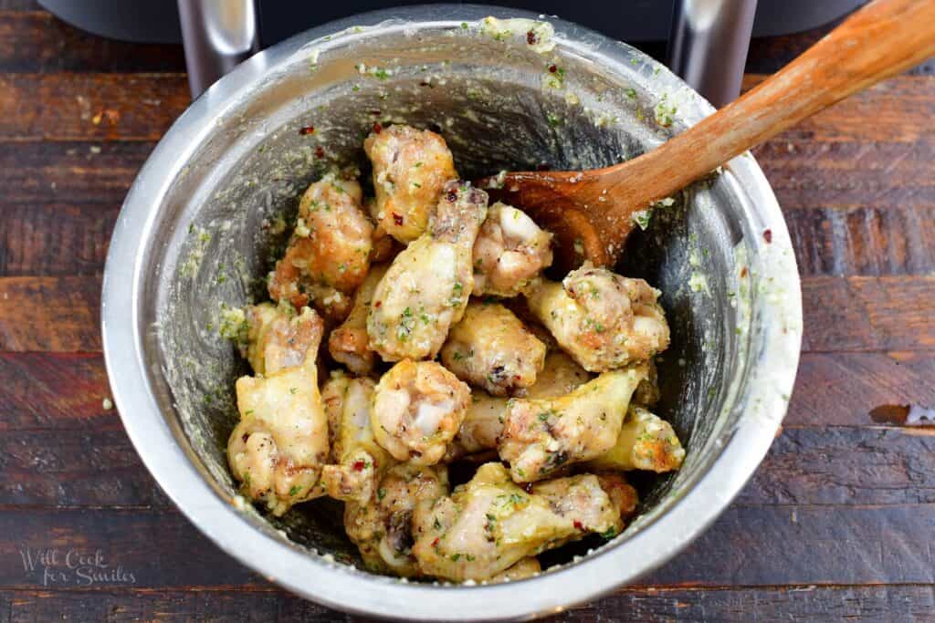 par-cooked chicken wings tossed with garlic and parmesan sauce in a bowl