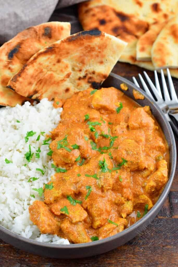 top view of butter chicken over rice with a naan in a bowl