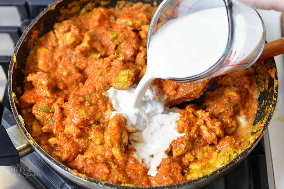 adding cream into butter chicken cooking in a pan