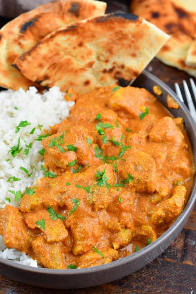 closeup of butter chicken over rice in a bowl