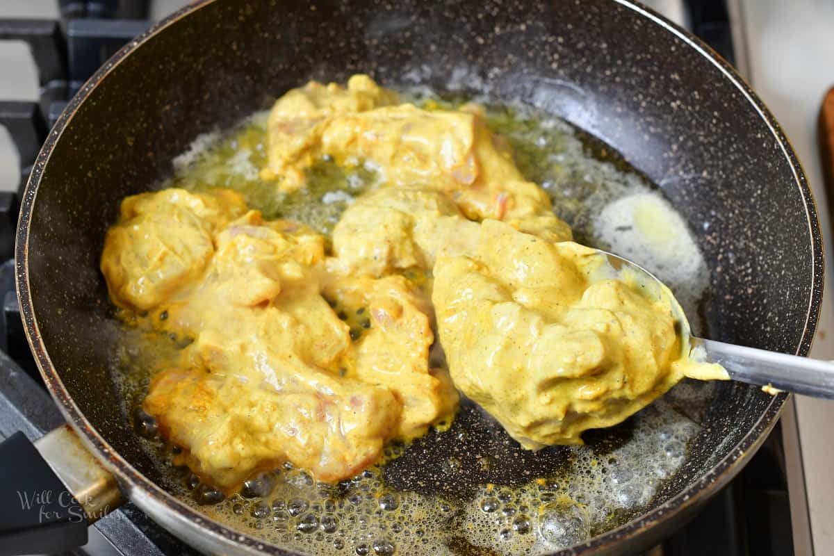 adding some chicken into the pan to saute