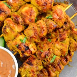 closeup of several skewers of chicken satay stacked