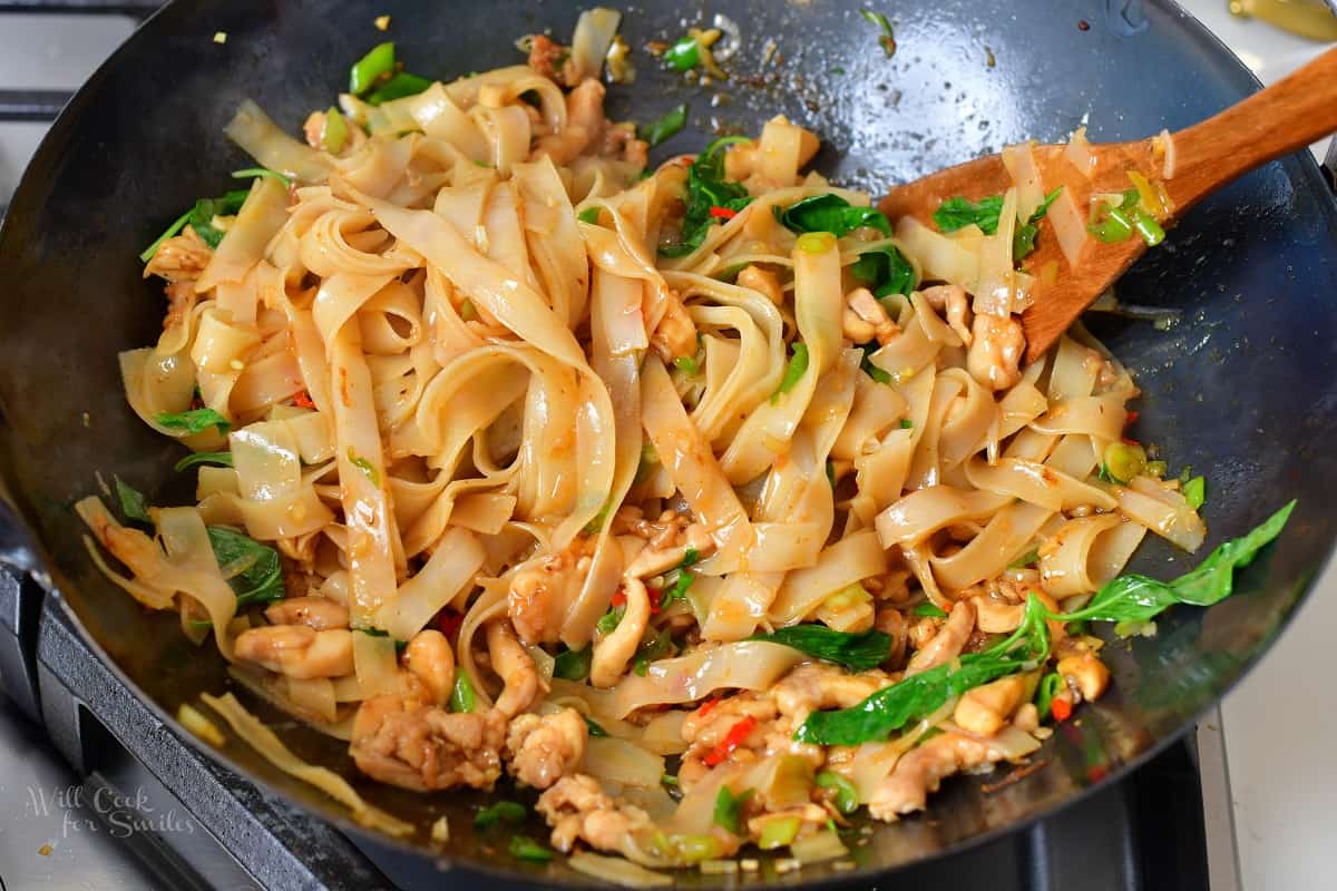 tossing the noodles chicken and veggies with sauce