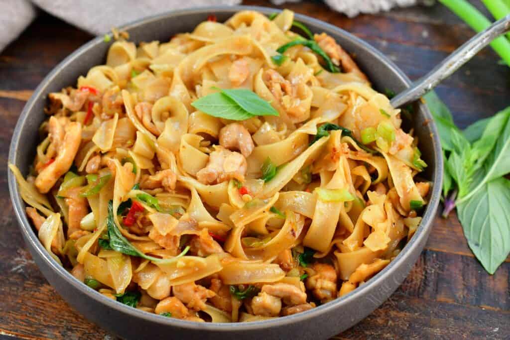 side view of cooked drunken noodles in a bowl with basil