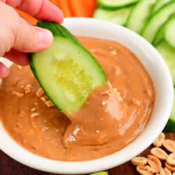 dipping cucumber into the peanut sauce