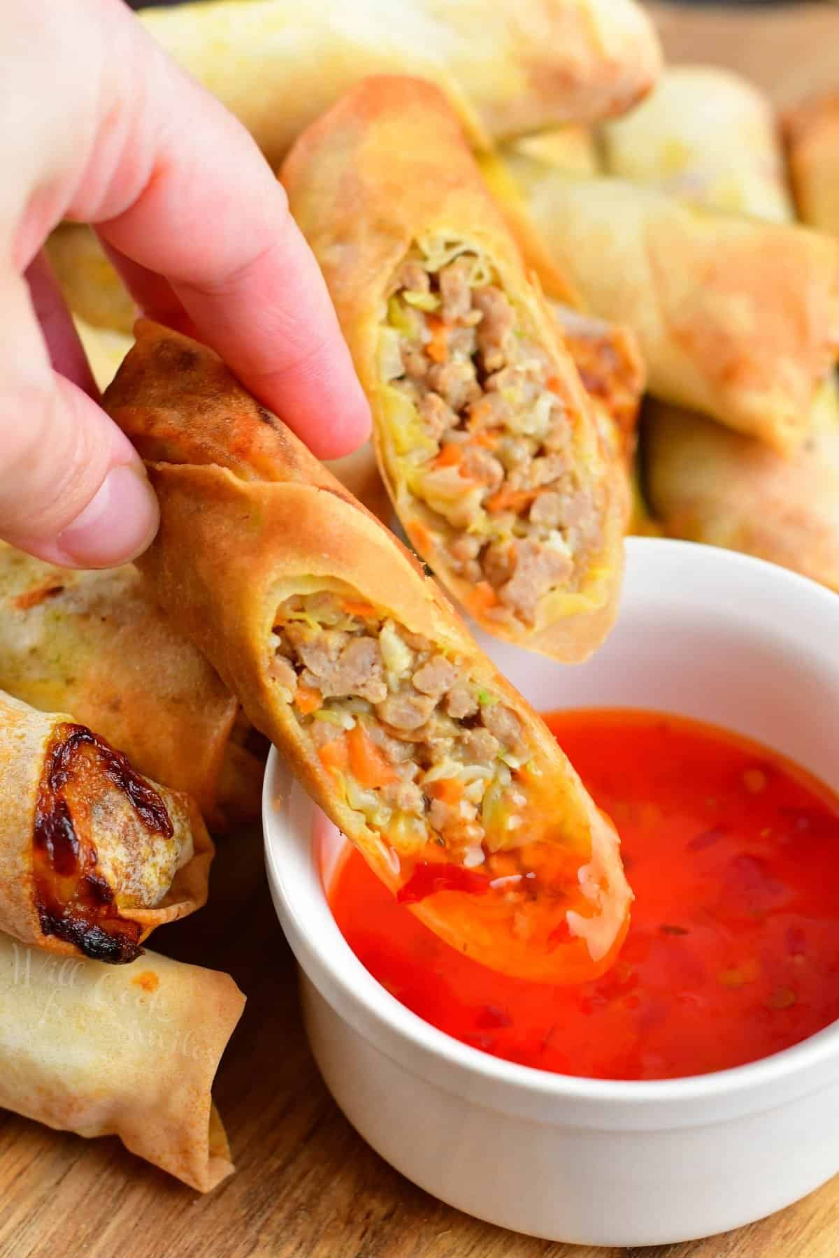 dipping a Thai spring roll half into some sweet Thai chili sauce. 