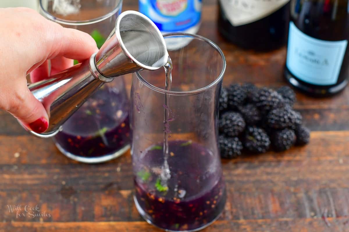 pouring in gin to the mashed blackberries