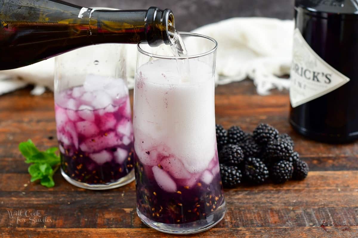 pouring in champagne to blackberry cocktail