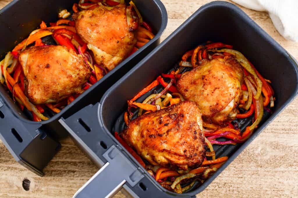 cooked chicken thighs and peppers in air fryer basket
