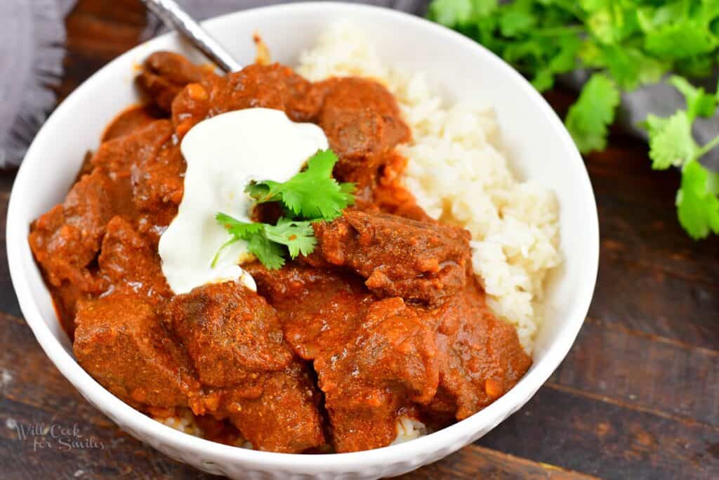 closeup of lamb Rogan Josh in a bowl with rice and yogurt