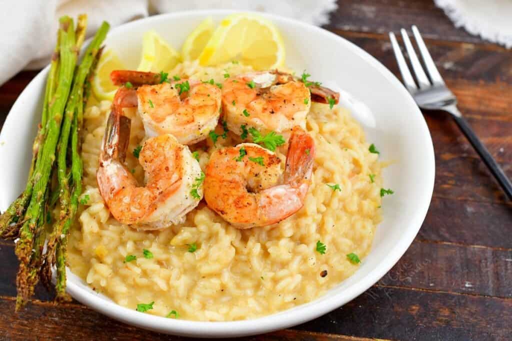 closeup side of risotto topped with shrimp and asparagus