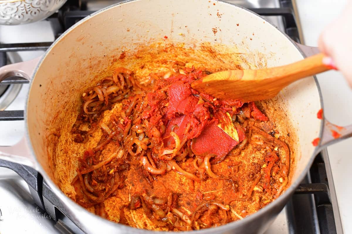 stirring in tomato paste into the onions and spices