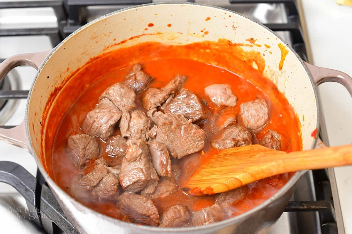adding lamb back to the pot with the tomato sauce