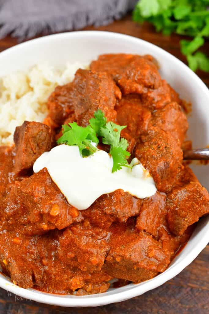 spooning out some lamb Rogan Josh from the bowl