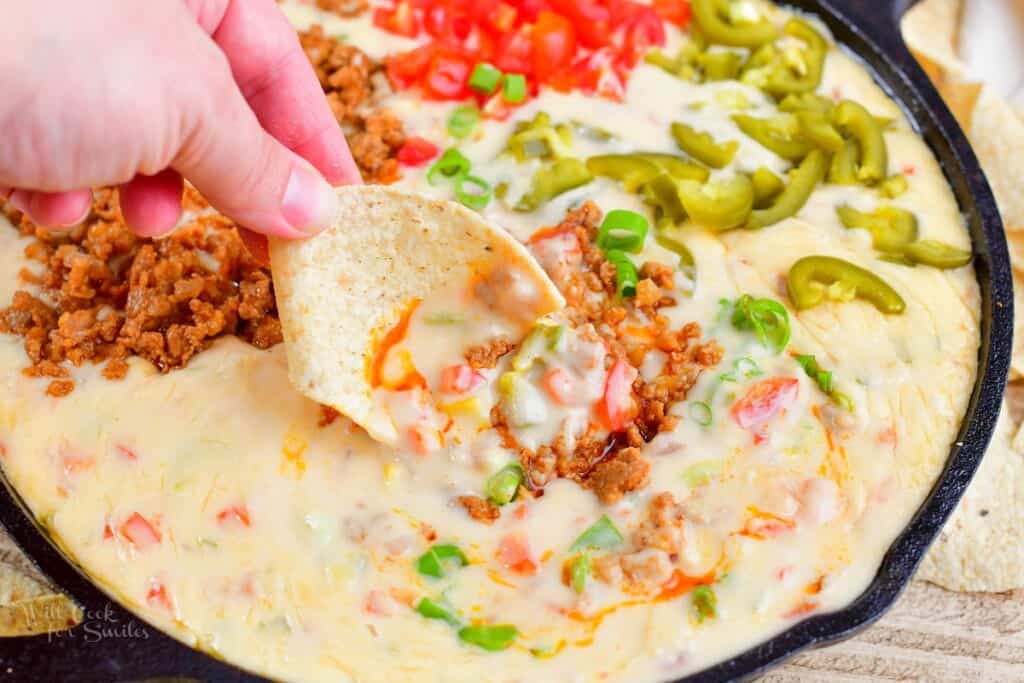 closeup of scooping out some queso with toppings