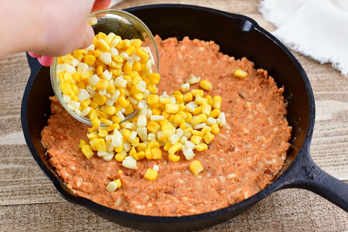 spreading corn over refried bean mixture