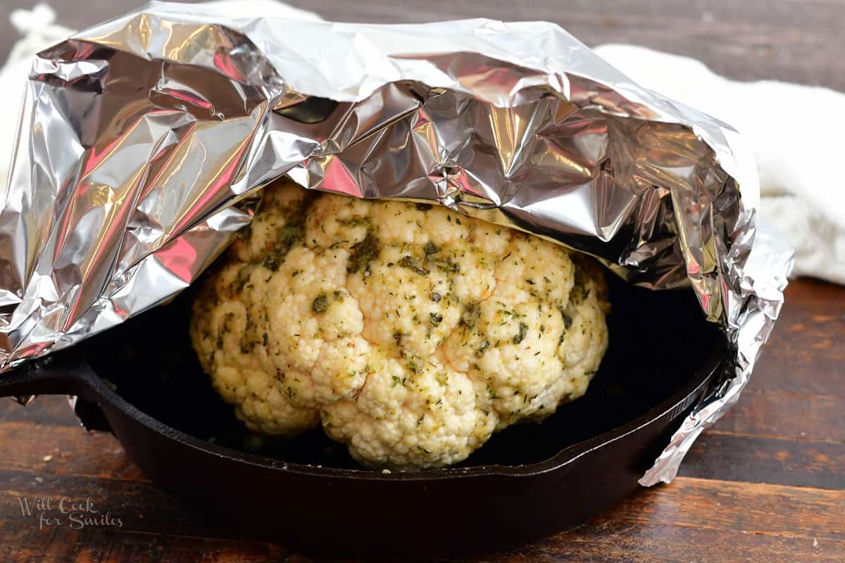 seasoned head of cauliflower in a skillet with foil