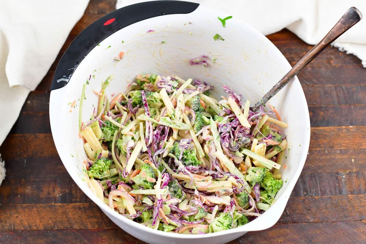 mixing the slaw in a white mixing bowl