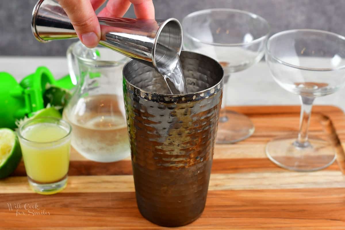 pouring in light rum into the cocktail shaker