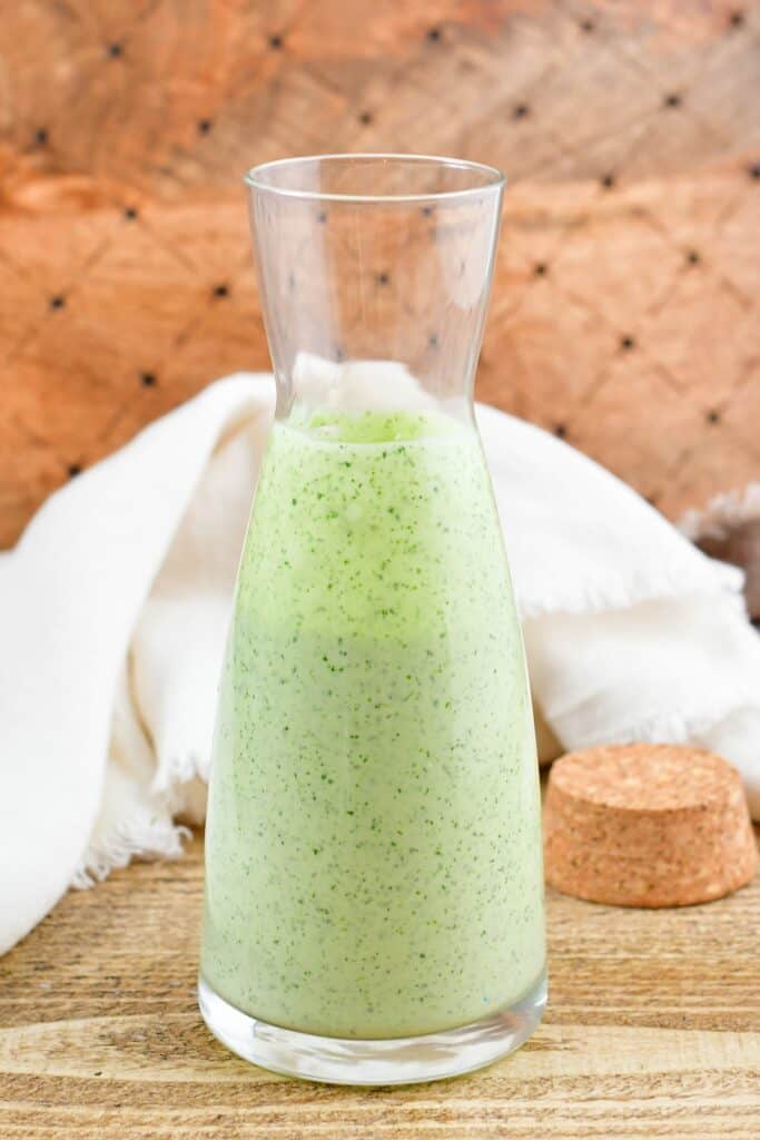 open tall glass jar filled with creamy green dressing