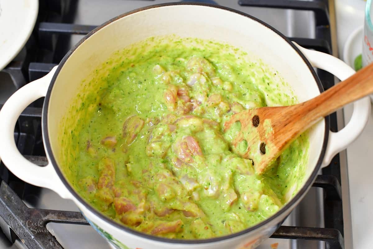 stirring in chicken into the creamy green curry broth