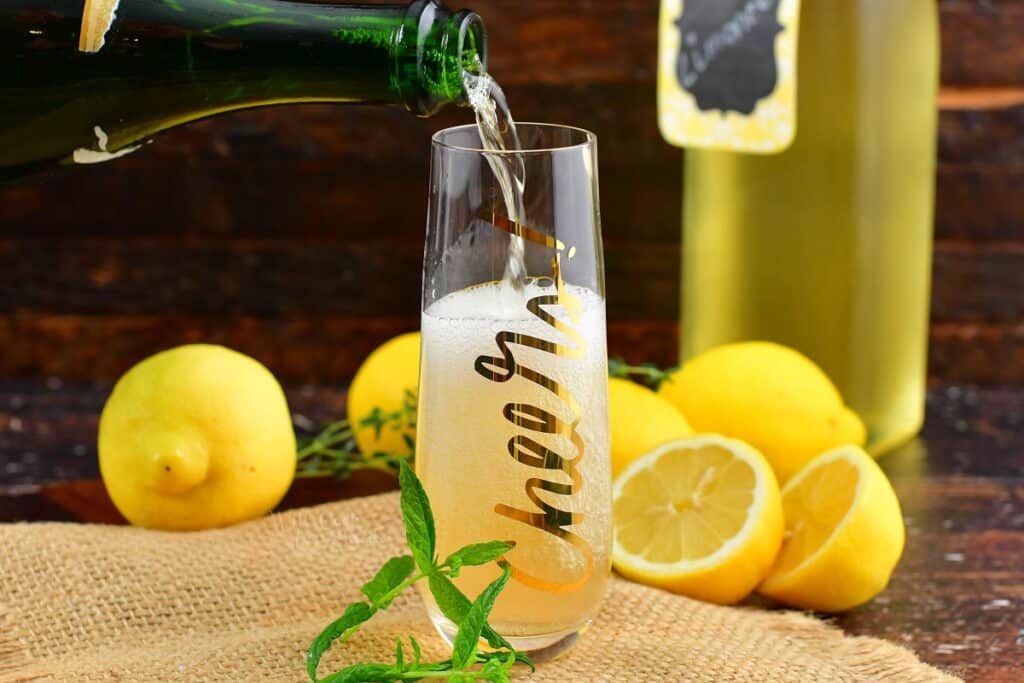 pouring in champagne into the tall glass with limoncello